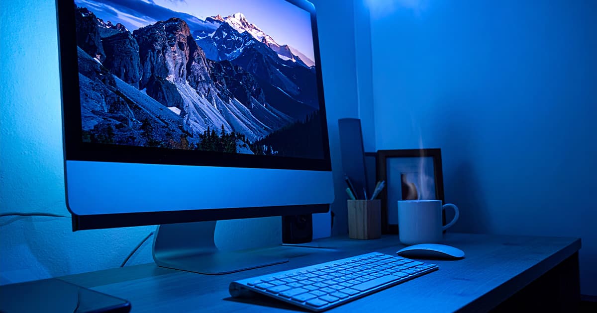 パソコンとキーボード、コーヒー、デスクの上でブルー背景